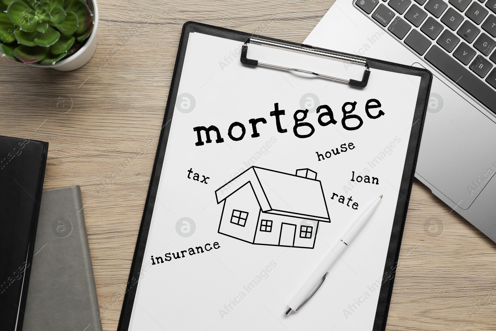 Image of Mortgage. Paper with drawing of house and words on wooden table. Workplace with laptop, top view