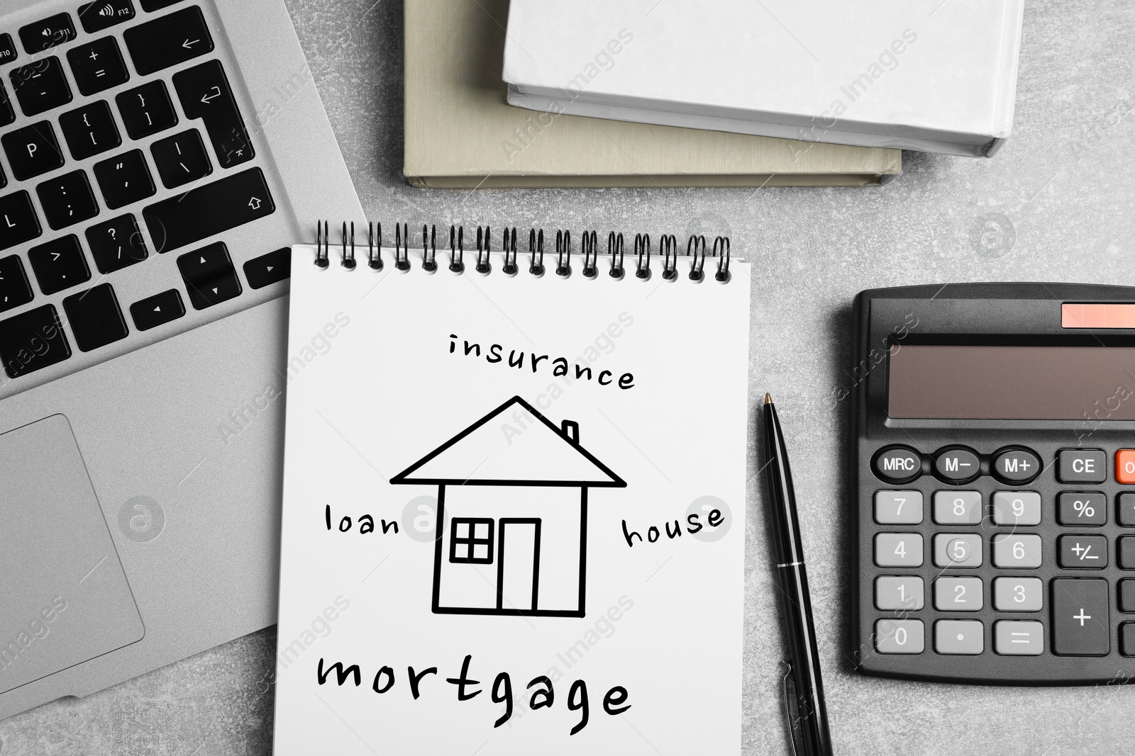 Image of Mortgage. Notebook with drawing of house and words on grey table. Workplace with laptop, top view