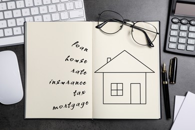 Image of Mortgage. Notebook with drawing of house and words on black table. Workplace with computer keyboard and mouse, top view