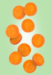 Round carrot slices in air on light green background