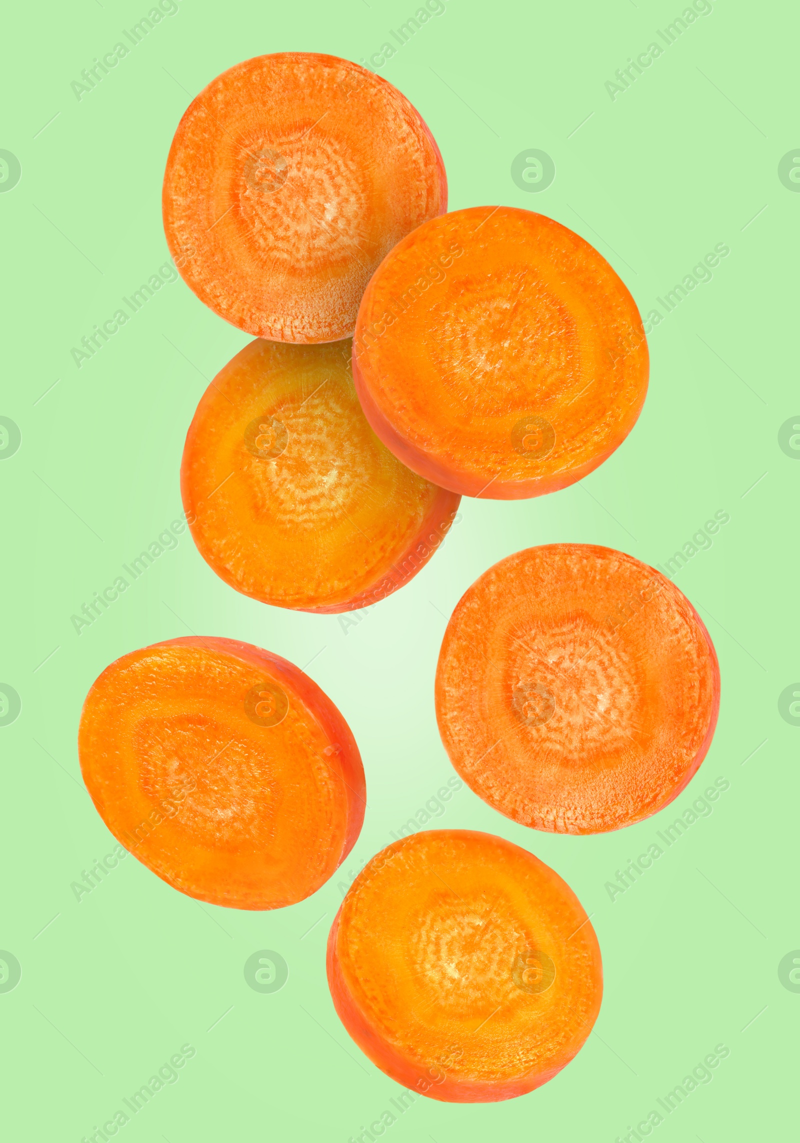 Image of Round carrot slices in air on light green background