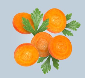 Image of Round carrot slices and parsley in air on grey background