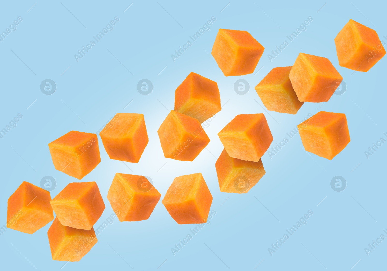 Image of Carrot cubes in air on light blue background