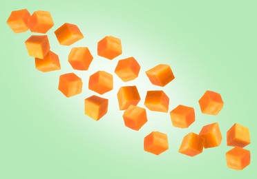 Image of Carrot cubes in air on light green background