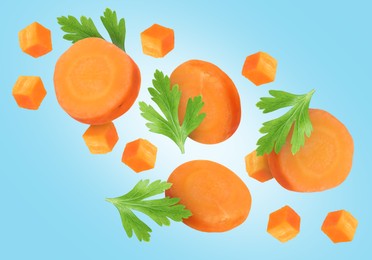 Sliced carrot and parsley in air on light blue background