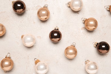 Photo of Many shiny Christmas tree baubles on light textured table, flat lay