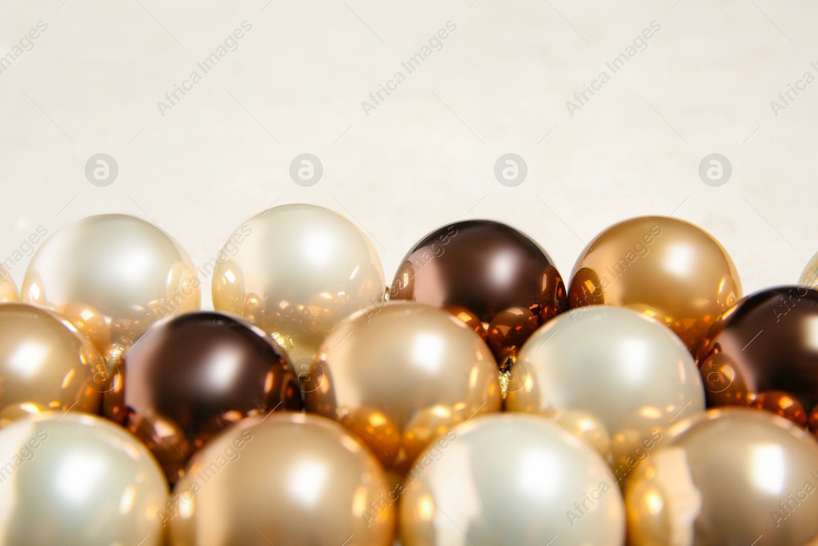 Photo of Many shiny Christmas tree baubles on light background, closeup