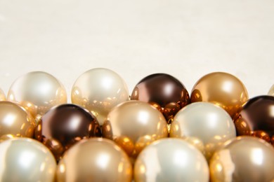 Photo of Many shiny Christmas tree baubles on light background, closeup