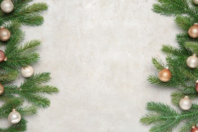 Photo of Christmas decor. Fir tree branches and shiny baubles on light textured table, flat lay. Space for text