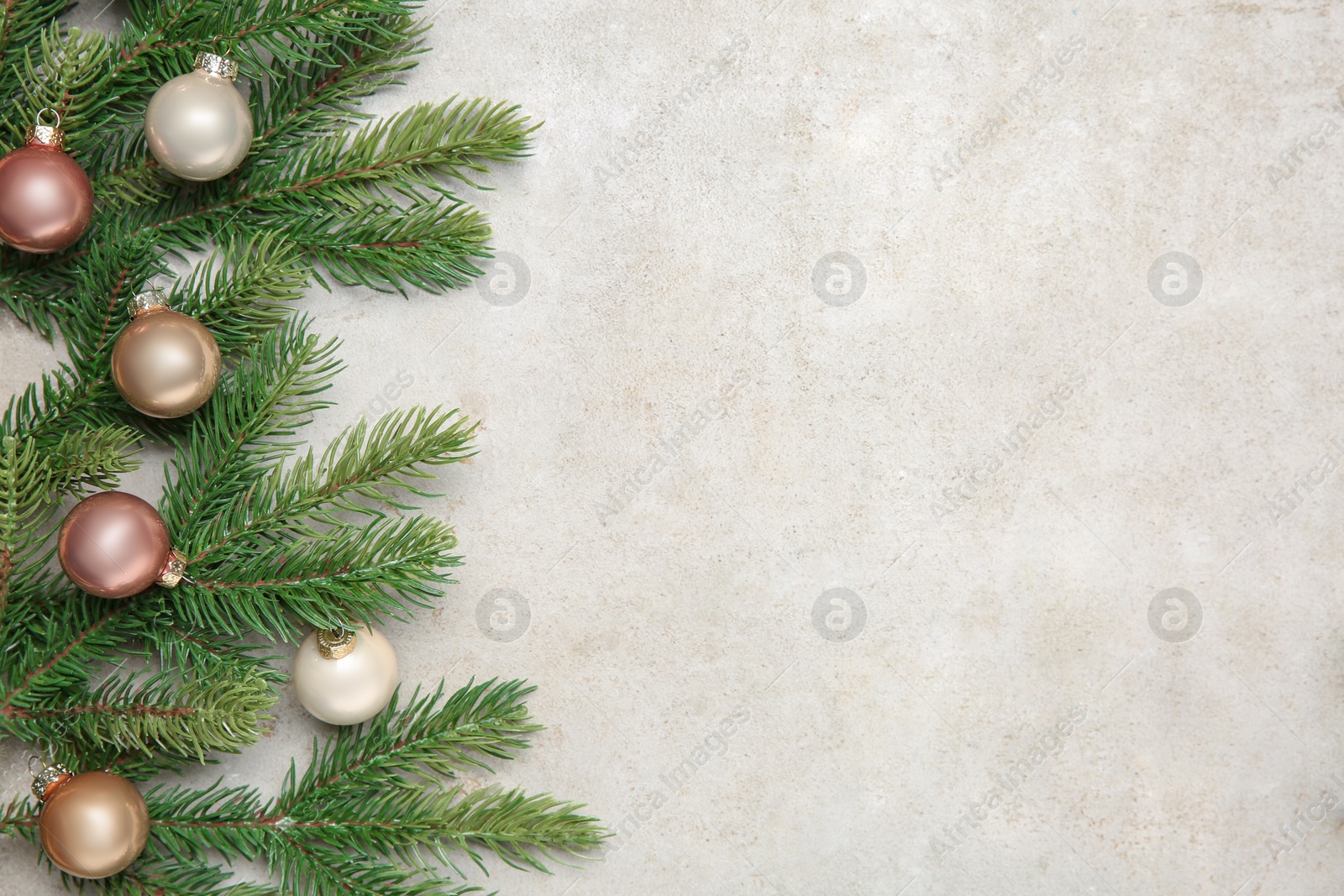 Photo of Christmas decor. Fir tree branches and shiny baubles on light textured table, flat lay. Space for text