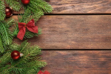 Photo of Fir tree branches with Christmas decor on wooden table, flat lay. Space for text