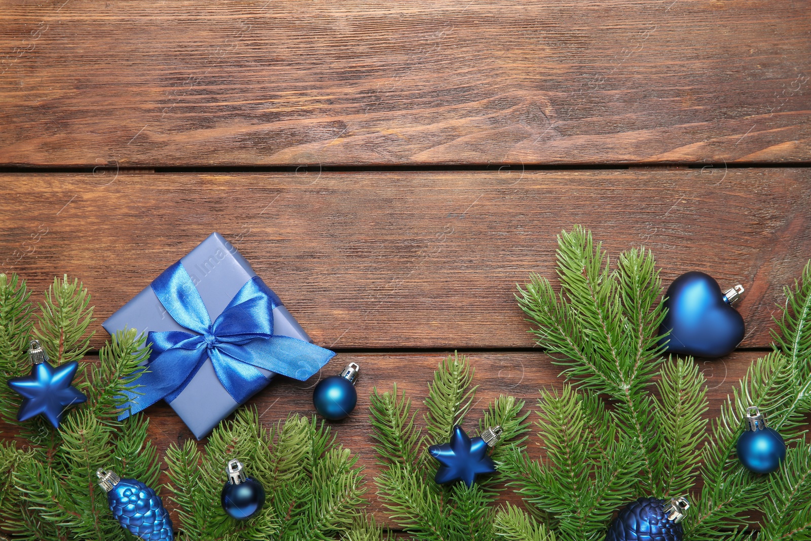 Photo of Fir tree branches with Christmas decor and gift box on wooden table, flat lay. Space for text