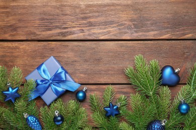 Photo of Fir tree branches with Christmas decor and gift box on wooden table, flat lay. Space for text