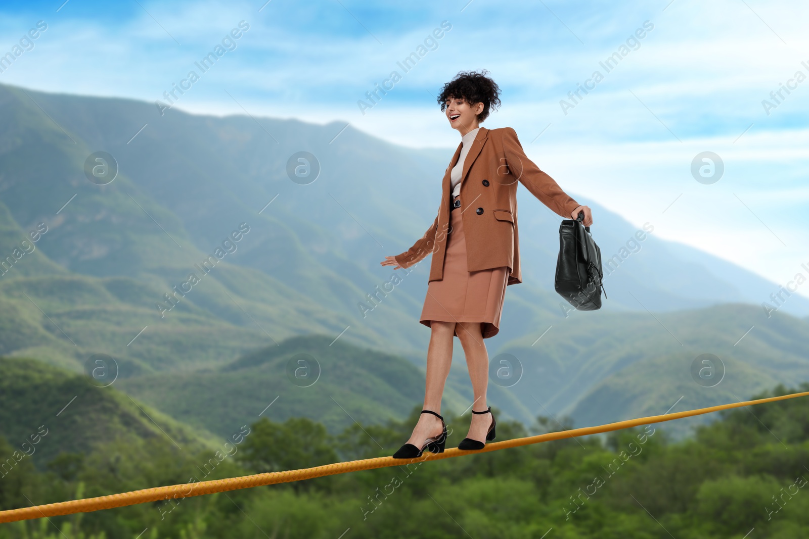 Image of Businesswoman walking rope in mountains. Concept of risk and balance