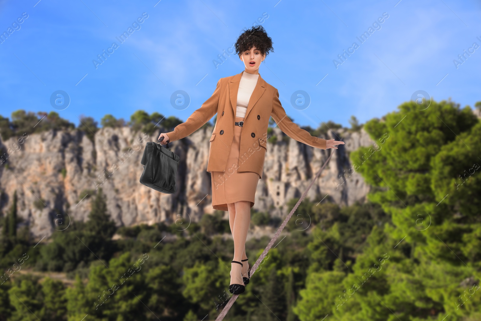 Image of Businesswoman walking rope in mountains. Concept of risk and balance