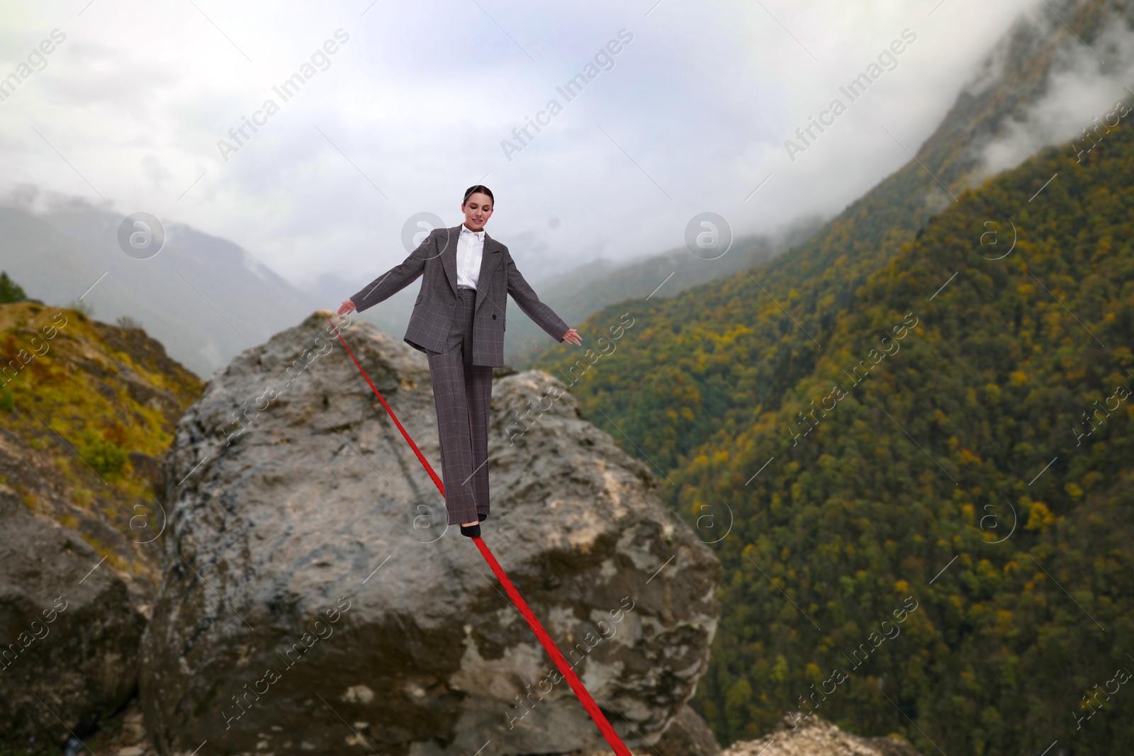 Image of Businesswoman walking rope in mountains. Concept of risk and balance