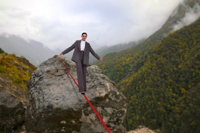 Businesswoman walking rope in mountains. Concept of risk and balance