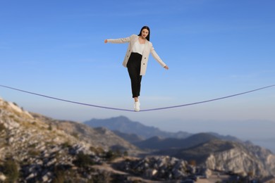 Businesswoman walking rope in mountains. Concept of risk and balance