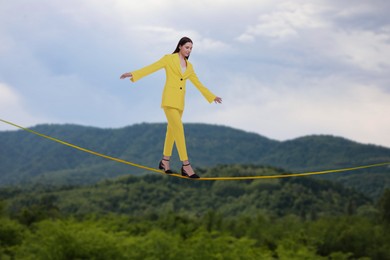 Businesswoman walking rope in mountains. Concept of risk and balance