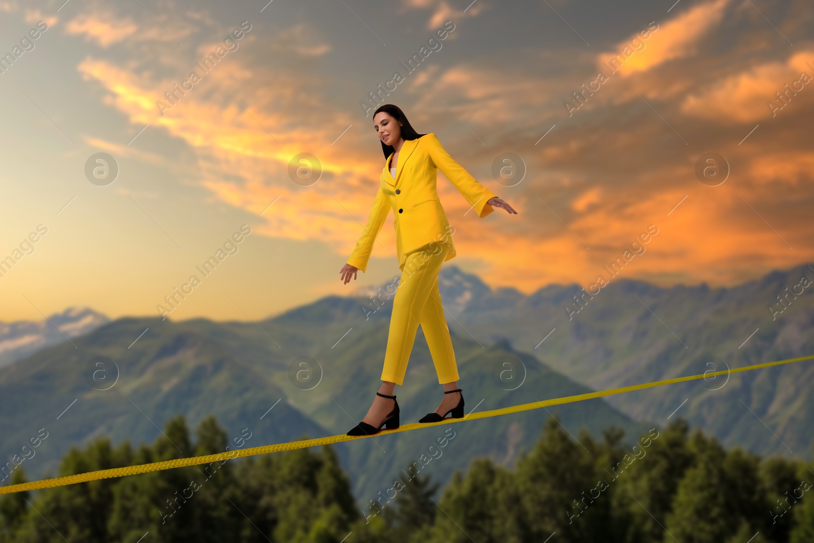 Image of Businesswoman walking rope in mountains. Concept of risk and balance