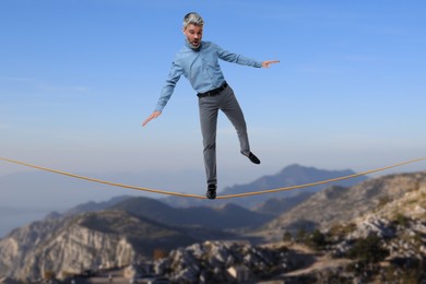 Image of Businessman walking rope in mountains. Concept of risk and balance