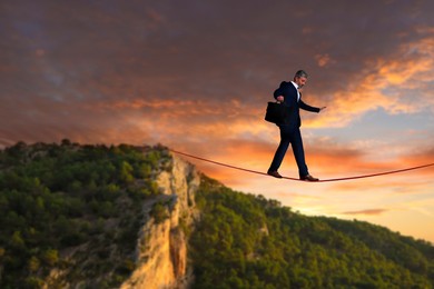 Image of Businessman walking rope in mountains. Concept of risk and balance