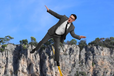 Businessman walking rope in mountains. Concept of risk and balance