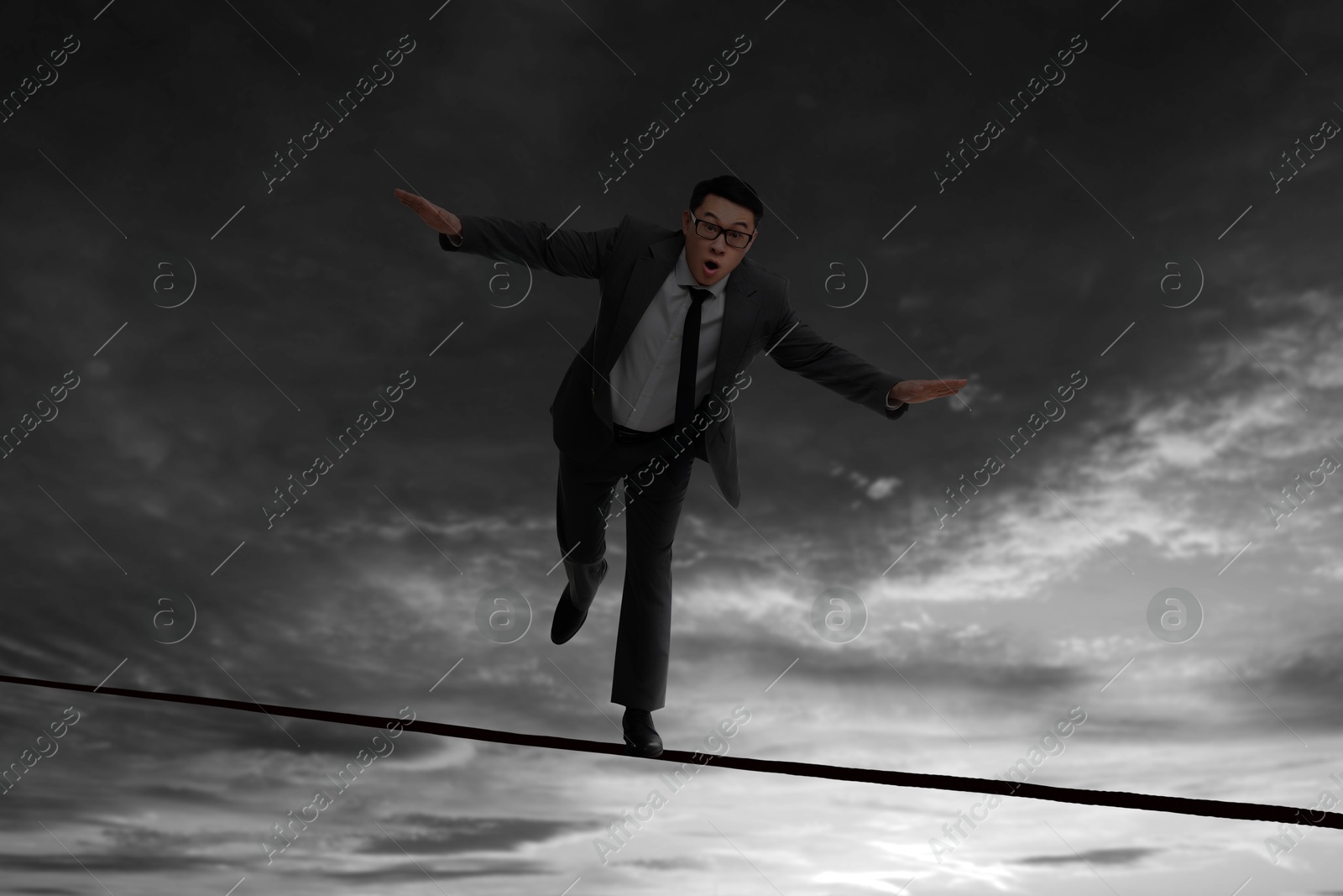 Image of Businessman walking rope in mountains. Concept of risk and balance