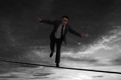 Image of Businessman walking rope in mountains. Concept of risk and balance