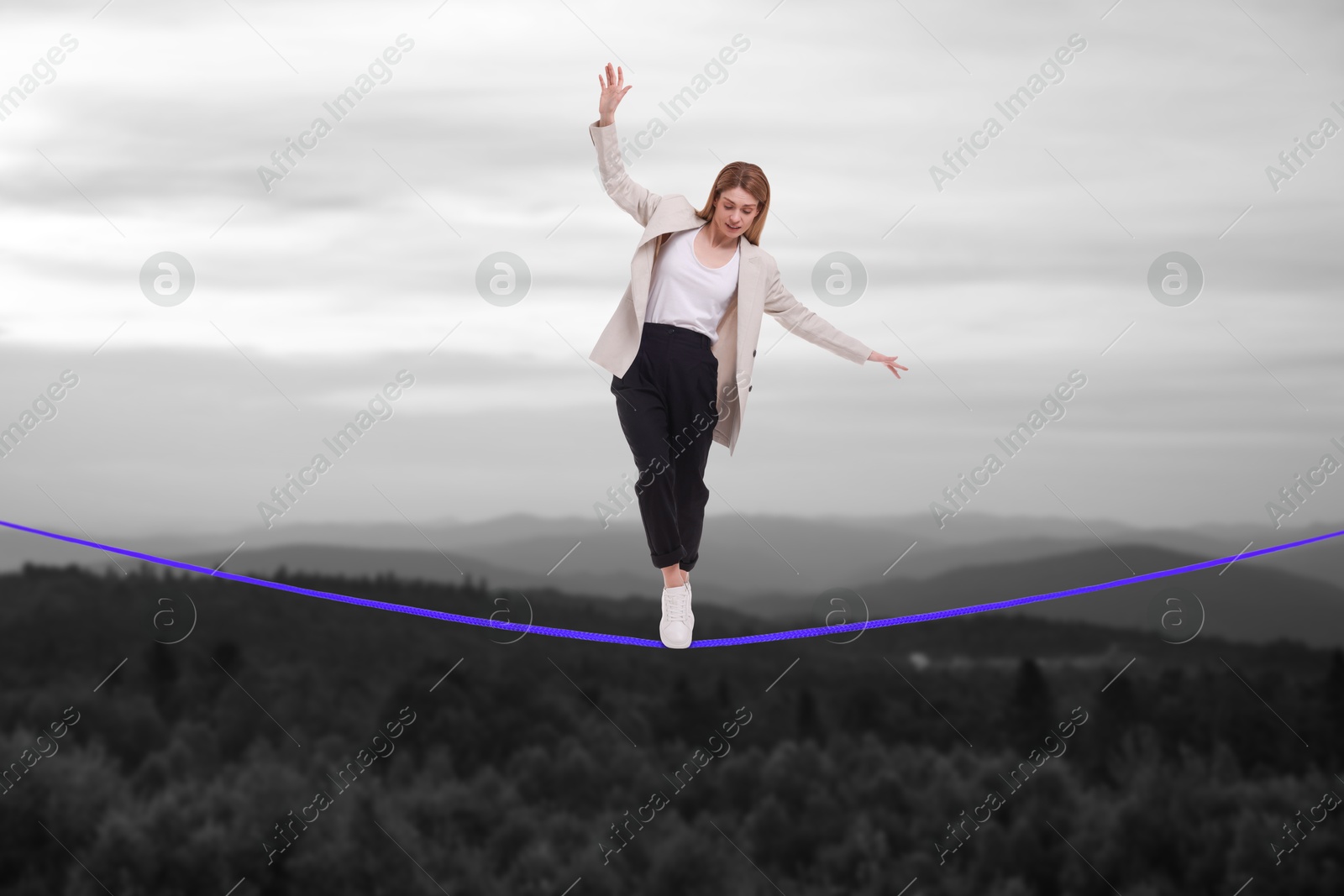 Image of Businesswoman walking rope in mountains. Concept of risk and balance