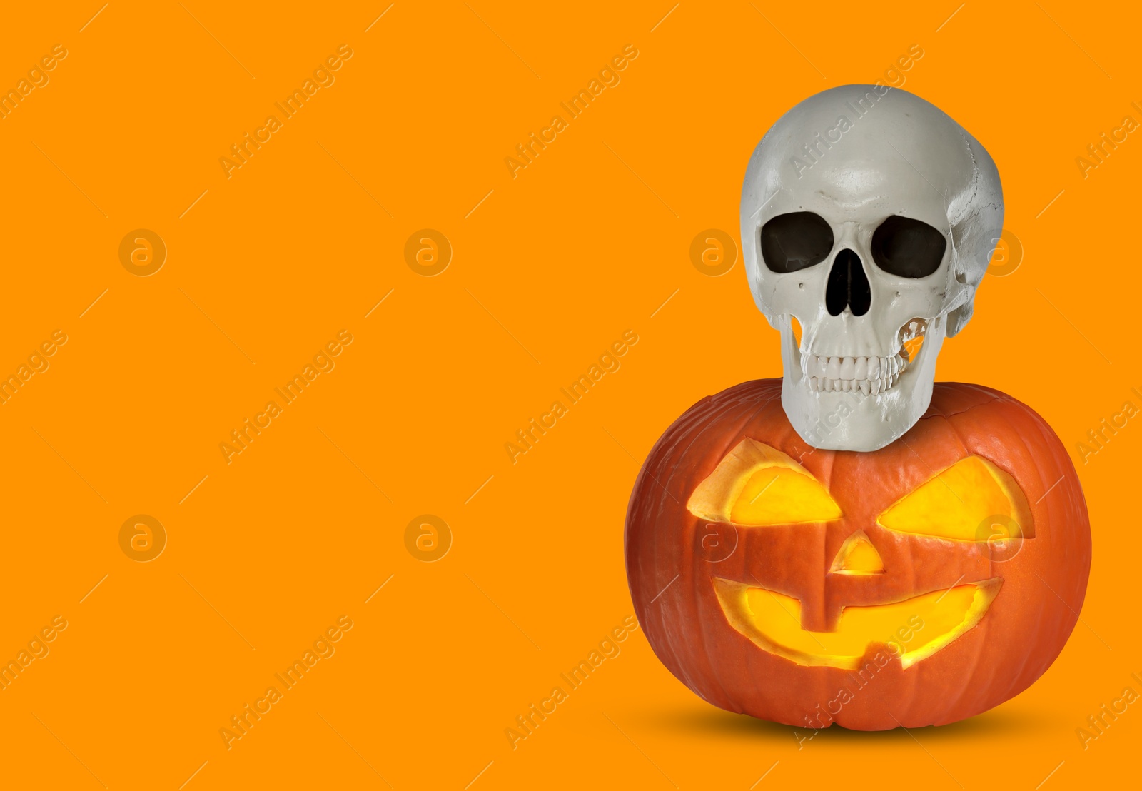 Image of Spooky glowing jack o'lantern and scary skull on orange background, space for text. Halloween celebration