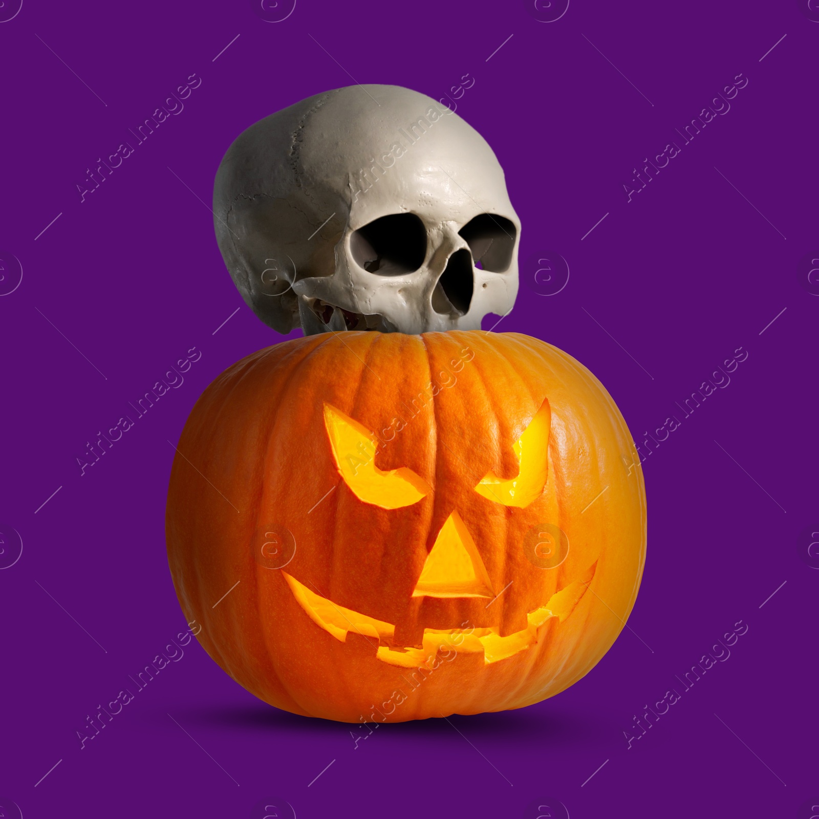 Image of Spooky glowing jack o'lantern and scary skull on purple background. Halloween celebration