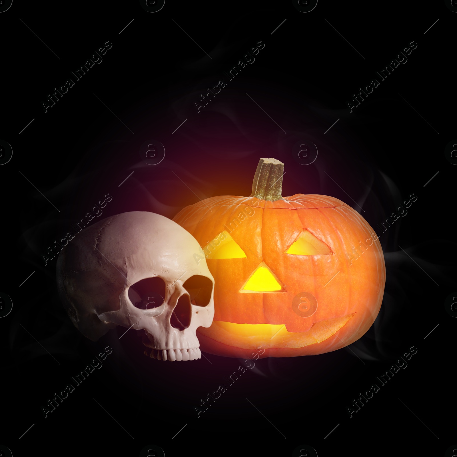 Image of Spooky glowing jack o'lantern and scary skull on black background. Halloween celebration