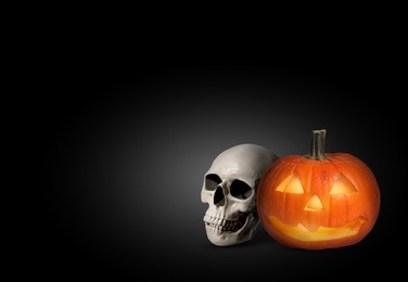 Image of Spooky glowing jack o'lantern and scary skull on black background, space for text. Halloween celebration