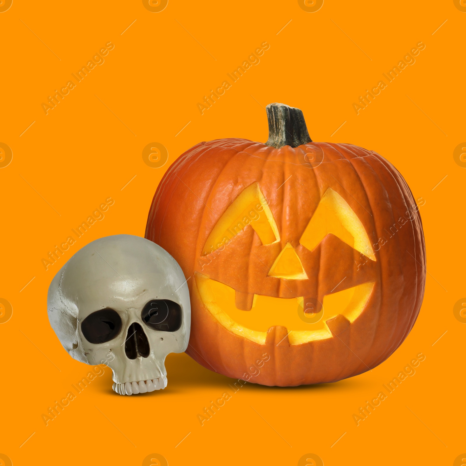 Image of Spooky glowing jack o'lantern and scary skull on orange background. Halloween celebration