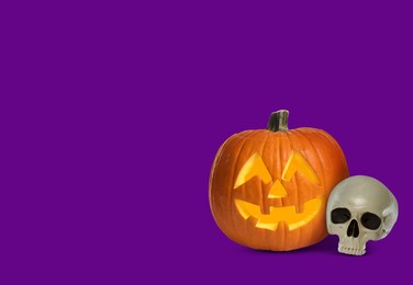 Image of Spooky glowing jack o'lantern and scary skull on purple background, space for text. Halloween celebration