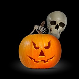 Image of Scary skeleton touching spooky jack o'lantern on black background. Halloween celebration