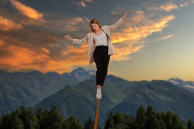 Businesswoman walking rope in mountains. Concept of risk and balance