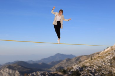 Businesswoman walking rope in mountains. Concept of risk and balance