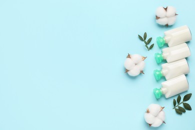 Photo of Cosmetic products, leaves and cotton flowers on light blue background, flat lay. Space for text