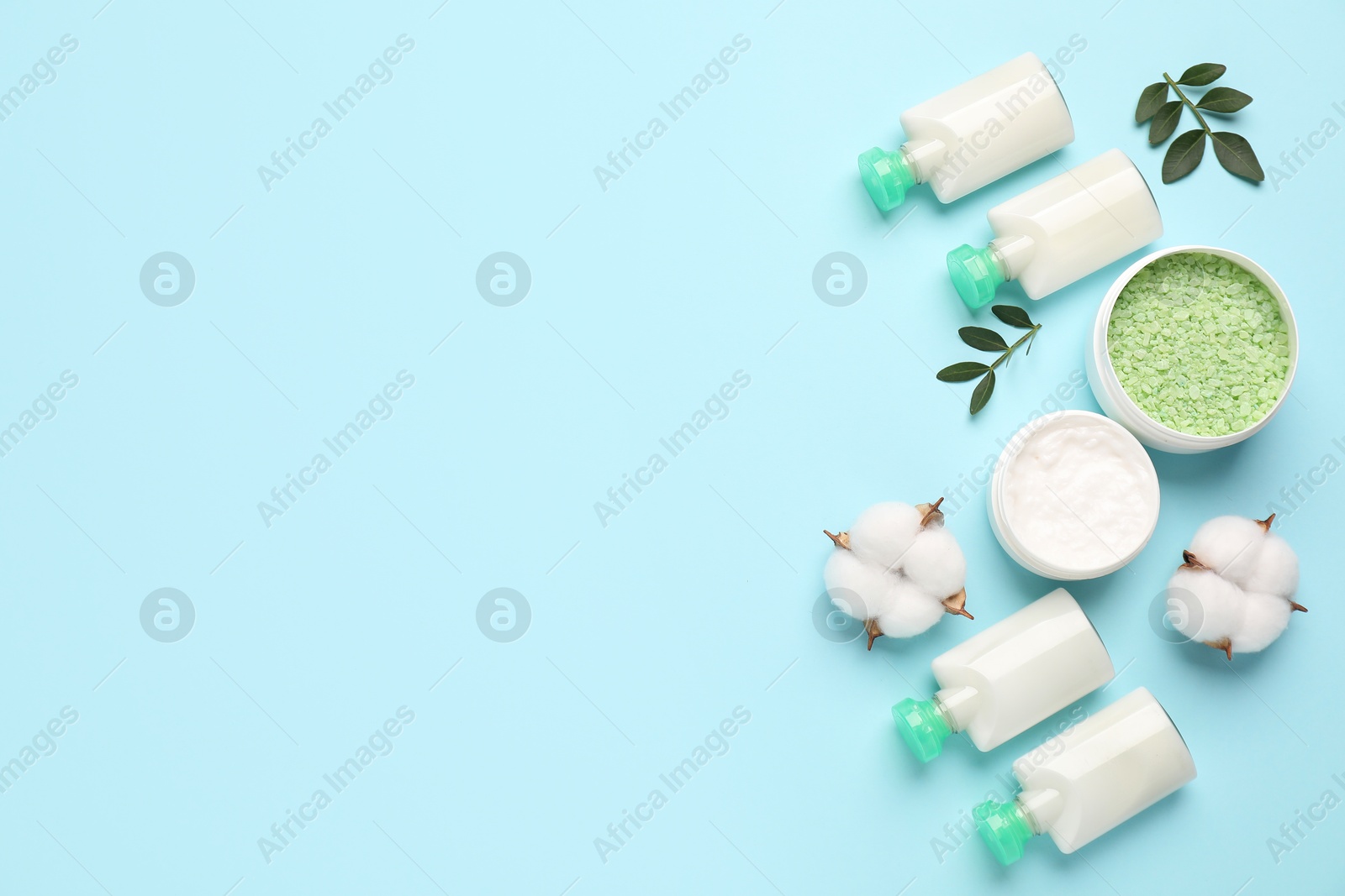 Photo of Different cosmetic products, leaves and cotton flowers on light blue background, flat lay. Space for text