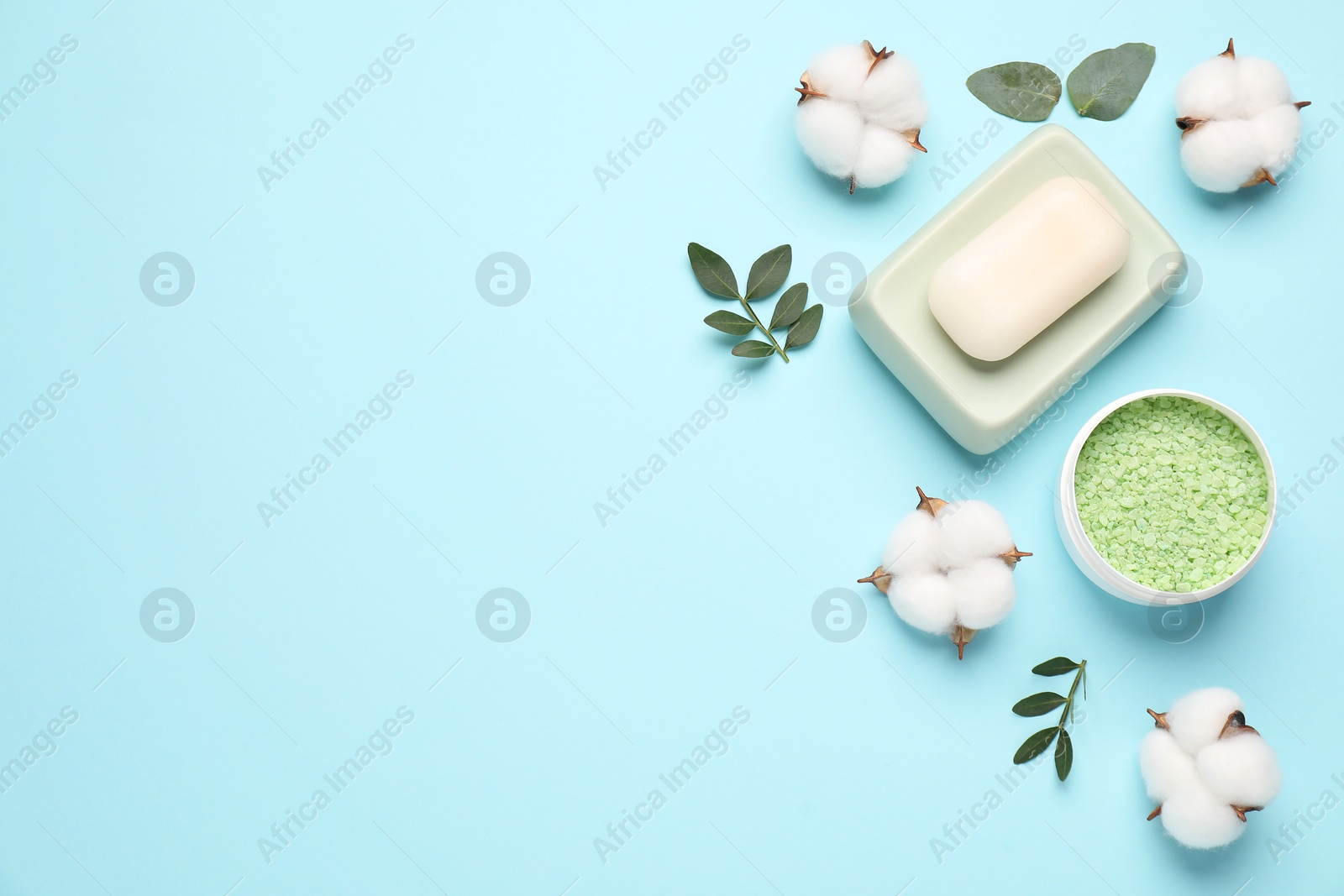 Photo of Different cosmetic products, leaves and cotton flowers on light blue background, flat lay. Space for text