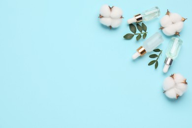 Photo of Cosmetic products. Essential oil, leaves and cotton flowers on light blue background, flat lay. Space for text