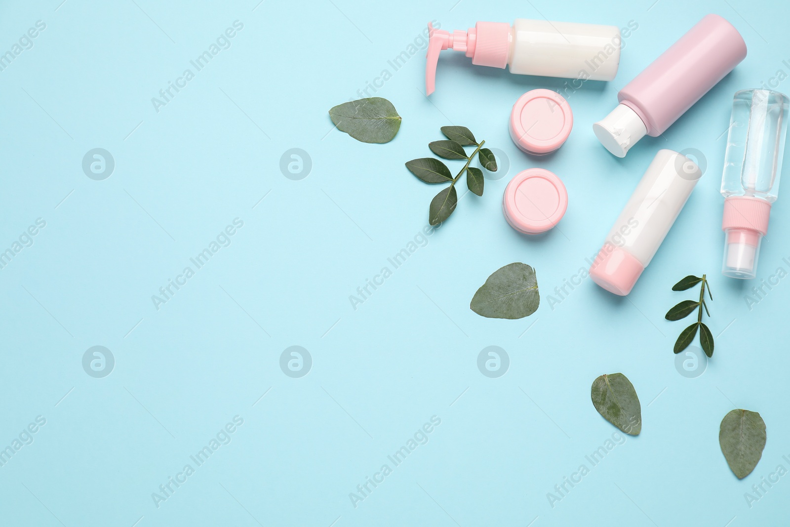 Photo of Different cosmetic products and leaves on light blue background, flat lay. Space for text