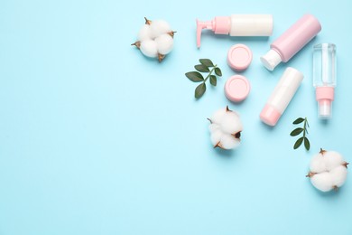 Photo of Different cosmetic products, leaves and cotton flowers on light blue background, flat lay. Space for text