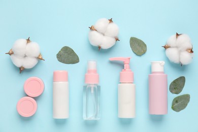 Different cosmetic products, leaves and cotton flowers on light blue background, flat lay