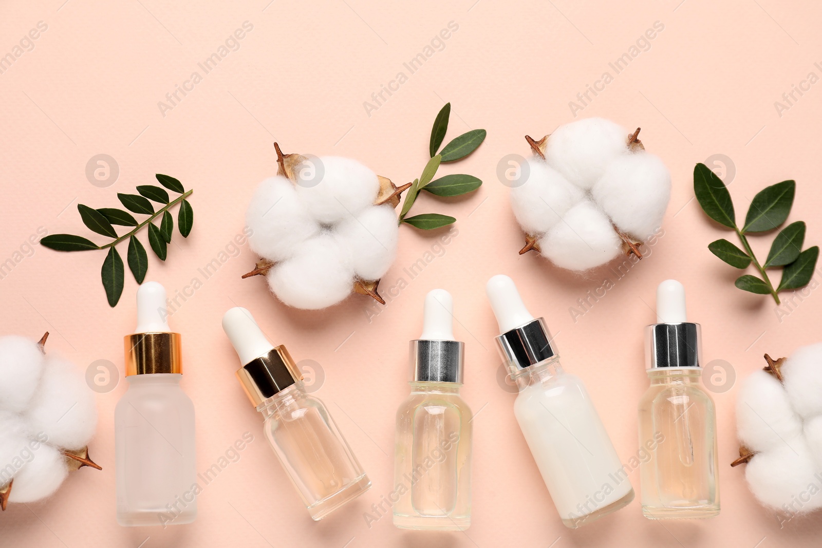 Photo of Different cosmetic products, cotton flowers and green leaves on beige background, flat lay