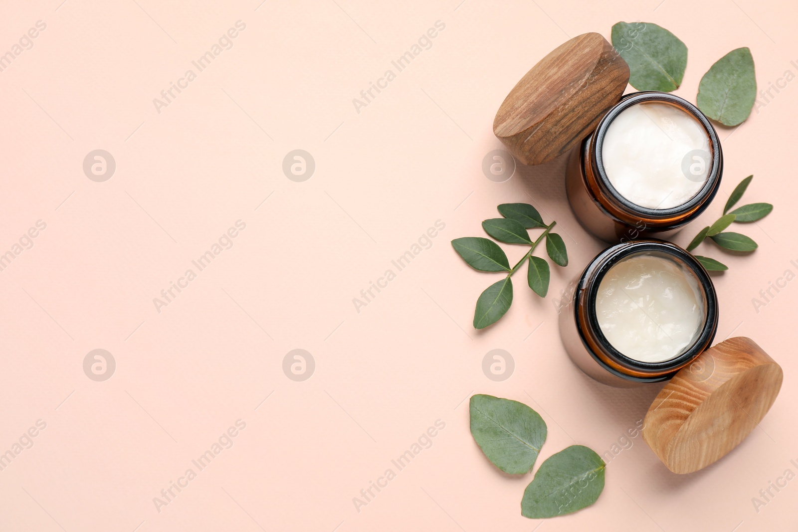 Photo of Different cosmetic products and green leaves on beige background, flat lay. Space for text