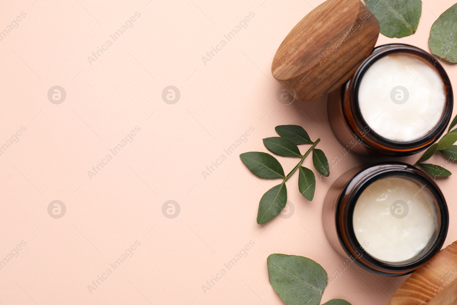 Photo of Different cosmetic products and green leaves on beige background, flat lay. Space for text