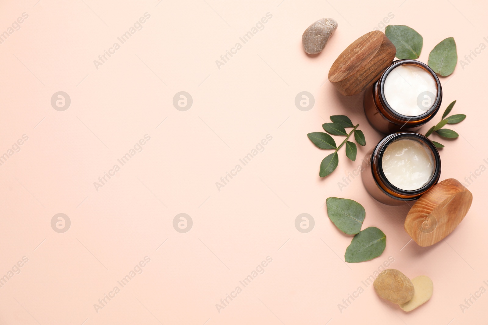 Photo of Different cosmetic products and green leaves on beige background, flat lay. Space for text